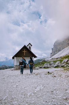 couple hiking in the italian dolomites during foggy weather with clouds, Stunning view to Tre Cime peaks in Dolomites, Italy. Europe