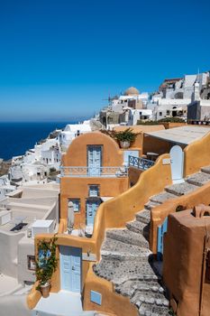 Santorini, Greece. Picturesq view of traditional cycladic Santorini houses on small street with flowers in foreground. Location: Oia village, Santorini, Greece. Vacations background Europe