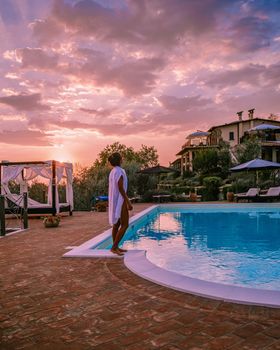 Luxury country house with swimming pool in Italy. Pool and old farm house during sunset central Italy. Couple on Vacation at luxury villa in Italy, men and woman watching sunset