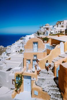 Santorini Greece, young couple on luxury vacation at the Island of Santorini watching sunrise by the blue dome church and whitewashed village of Oia Santorini Greece during sunrise during summer vacation, men and woman on holiday in Greece