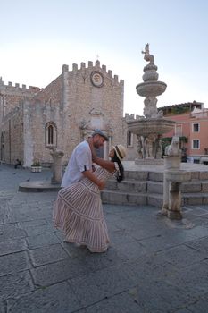 Taormina Sicily, Belvedere of Taormina and San Giuseppe church on the square Piazza IX Aprile in Taormina. Sicily, Italy. Couple on vacation at the Italian Island Sicily