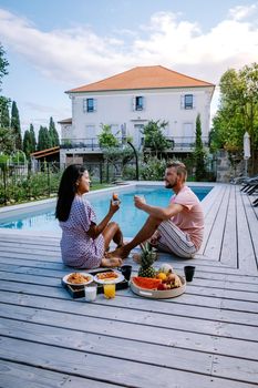 French vacation home with wooden deck and swimming pool in the Ardeche France Europe. Couple relaxing by the pool with wooden deck during luxury vacation at an holiday home in South of France