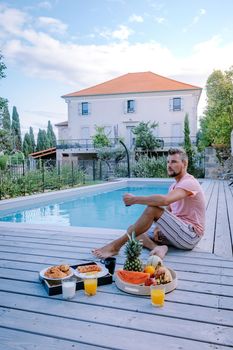 French vacation home with wooden deck and swimming pool in the Ardeche France Europe. guy relaxing by the pool with wooden deck during luxury vacation at an holiday home in South of France