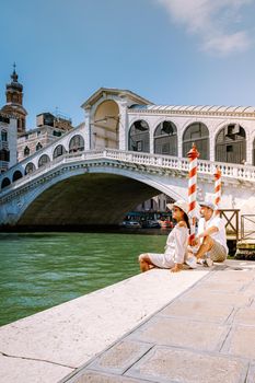 Venice Italy couple men and woman on a city trip at Venice, men and woman at waterfront looking at the famous Rialto bridge in Venice Italy. Europe