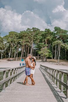 A lake situated in the Netherlands, Utrecht, called Henschotermeer. by drone aerial utrechtse heuvelrug, henschotermeer, lake in holland. Europe, couple men and woman walking on wooden pier
