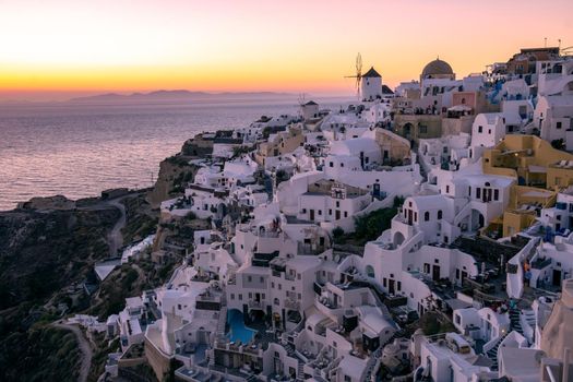 Sunset at the Island Of Santorini Greece, beautiful whitewashed village Oia with church and windmill during sunset, streets of Oia Santorini during summer vacation at the Greek Island