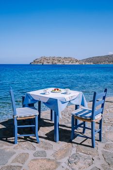 Crete Greece Plaka Lassithi with is traditional blue table and chairs and the beach in Crete Greece. Paralia Plakas, Plaka village Crete