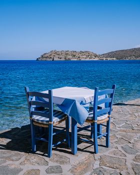 Crete Greece Plaka Lassithi with is traditional blue table and chairs and the beach in Crete Greece. Paralia Plakas, Plaka village Crete