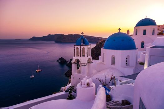 Sunset at the Island Of Santorini Greece, beautiful whitewashed village Oia with church and windmill during sunset, streets of Oia Santorini during summer vacation at the Greek Island