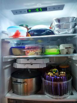 Open refrigerator shelves are stocked with groceries and fruits.