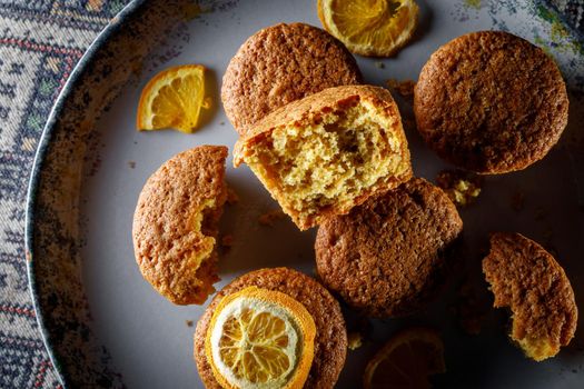 Fresh orange muffins on a round plate.