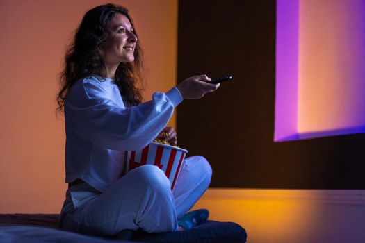 person watches a movie sitting on the couch with a bucket of popcorn.