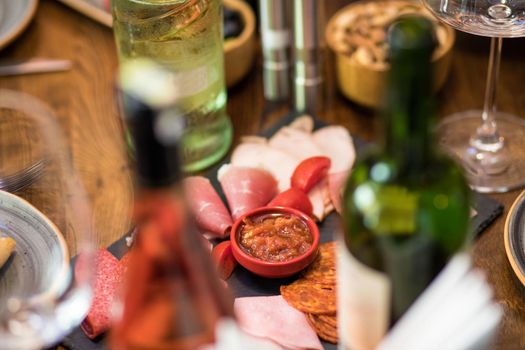 Tasty sausage with tomato and sauce with wine bottles