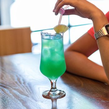 Woman holding glass of pineapple green cocktail