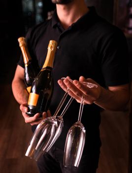 Man holding Champagne and glasses on dark background