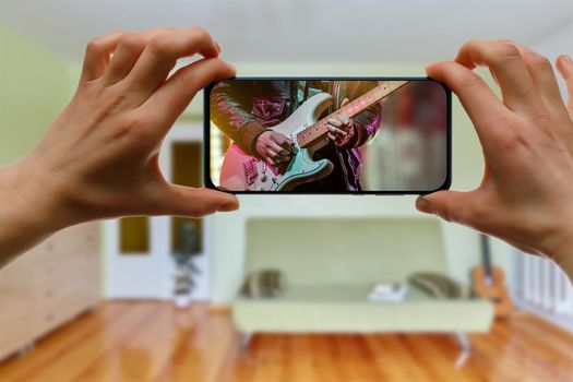 Watching online music concert at home using a mobile phone. Guitar close-up on the screen