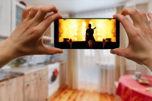 Watching online music concert at home using a mobile phone. Guitar close-up on the screen