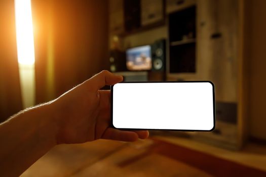 The concept of using a mobile phone at home. Blank white screen for your image.