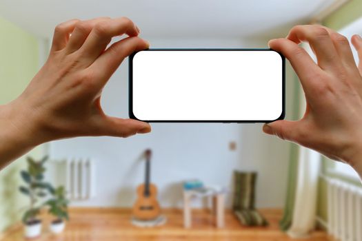 Mockup of using a smartphone in the home interior. Blank white screen for your idea