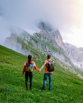 couple on vacation hiking in the Italien Dolomites, Amazing view on Seceda peak. Trentino Alto Adige, Dolomites Alps, South Tyrol, Italy, Europe. Odle mountain range, Val Gardena. Majestic Furchetta peak in morning sunlight. Italy