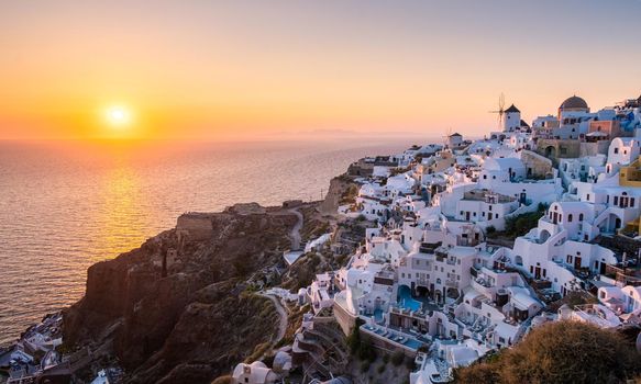 Sunset at the Island Of Santorini Greece, beautiful whitewashed village Oia with church and windmill during sunset, streets of Oia Santorini during summer vacation at the Greek Island