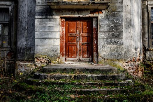 Porch of an old palace with a stone staircase and a red door