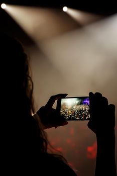 Mobile phone in hands at a music show. Using a smartphone concept