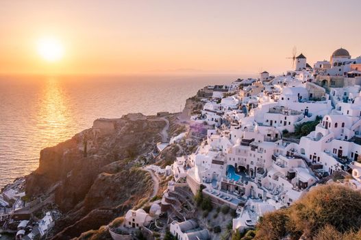 Sunset at the Island Of Santorini Greece, beautiful whitewashed village Oia with church and windmill during sunset, streets of Oia Santorini during summer vacation at the Greek Island