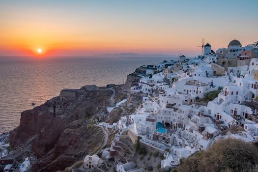 Sunset at the Island Of Santorini Greece, beautiful whitewashed village Oia with church and windmill during sunset, streets of Oia Santorini during summer vacation at the Greek Island