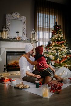 Family sitting on a floor. Couple near christmas tree, Christmas couple with present under christmas tree