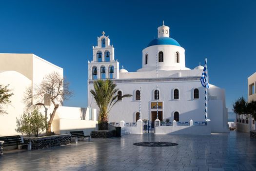 Sunset at the Island Of Santorini Greece, beautiful whitewashed village Oia with church and windmill during sunset, streets of Oia Santorini during summer vacation at the Greek Island