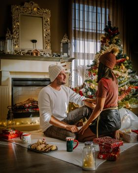 Family sitting on a floor. Couple near christmas tree, Christmas couple with present under christmas tree