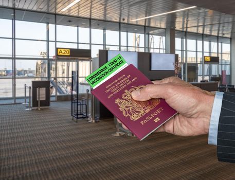 Mockup of airport terminal with businessman hand holding British passport and vaccination certificate to coronavirus