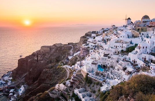 Sunset at the Island Of Santorini Greece, beautiful whitewashed village Oia with church and windmill during sunset, streets of Oia Santorini during summer vacation at the Greek Island