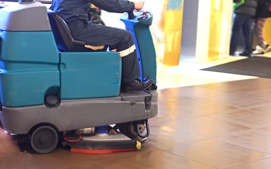Floor care and cleaning services with washing machine.Man driving professional cleaning machine at shopping centre.