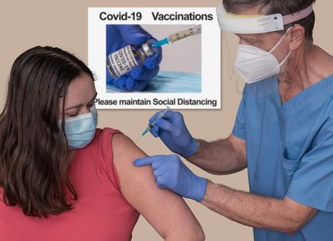 Senior man nurse with syringe injecting a young woman with the covid-19 vaccine in clinic or doctor office