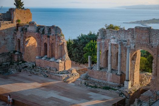 Ruins of Ancient Greek theatre in Taormina on background of Etna Volcano, Italy. Taormina located in Metropolitan City of Messina, on east coast of island of Sicily Europe