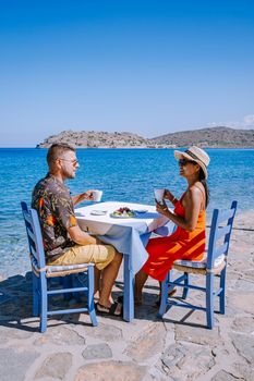 Crete Greece Plaka Lassithi with is traditional blue table and chairs and the beach in Crete Greece. Paralia Plakas, Plaka village Crete, couple on vacation holiday in Greece