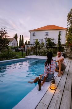 French vacation home with wooden deck and swimming pool in the Ardeche France Europe. Couple relaxing by the pool with wooden deck during luxury vacation at an holiday home in South of France
