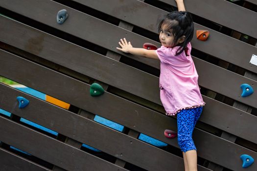 Pretty asian little girls while climbing in a playground