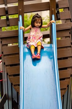 Pretty asian little girls while sliding in a playground