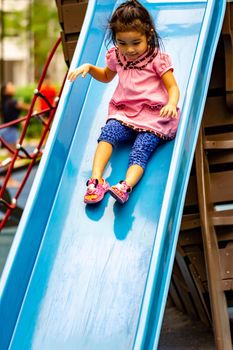 Pretty asian little girls while sliding in a playground