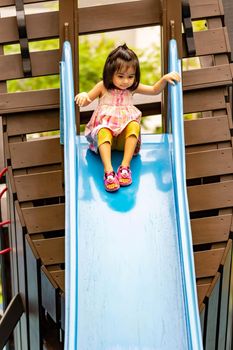 Pretty asian little girls while sliding in a playground