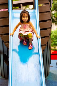 Pretty asian little girls while sliding in a playground