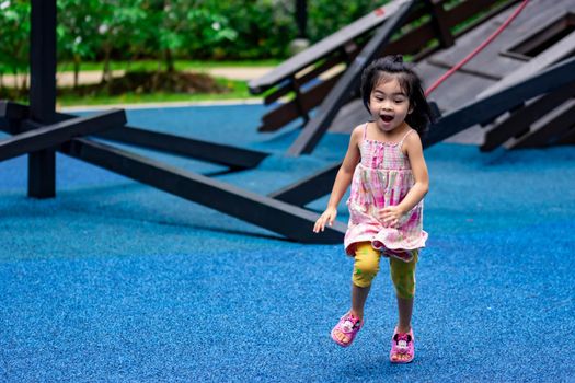 Cute little asian kid girl while running and enjoying on a playground