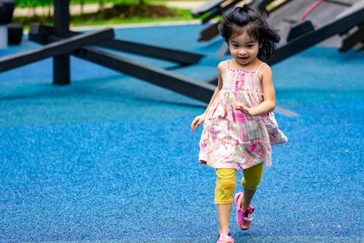 Cute little asian kid girl while running and enjoying on a playground