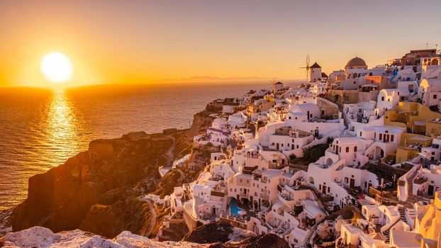 Sunset at the Island Of Santorini Greece, beautiful whitewashed village Oia with church and windmill during sunset, streets of Oia Santorini during summer vacation at the Greek Island