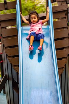 Pretty asian little girls while sliding in a playground