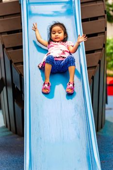 Pretty asian little girls while sliding in a playground