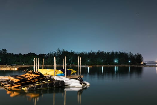 Landscape view of bridge, lake and nature with a bridge and some jetski. Bright night sky with stars and smooth light reflecting on waters somewhere in Asia